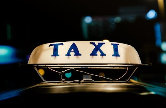 pexels-photo-590059-590059 Close-up view of an illuminated taxi sign in a bustling city at night.